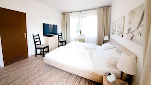 Een hotelkamer met een bed, een bureau met stoel, een televisie en een raam met gordijnen.