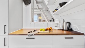 Une cuisine avec des meubles blancs, un plan de travail en bois et un porte-ustensiles suspendu.