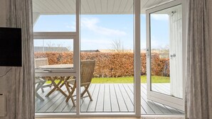 Une pièce dotée d’une porte-fenêtre coulissante donnant sur une terrasse extérieure.
