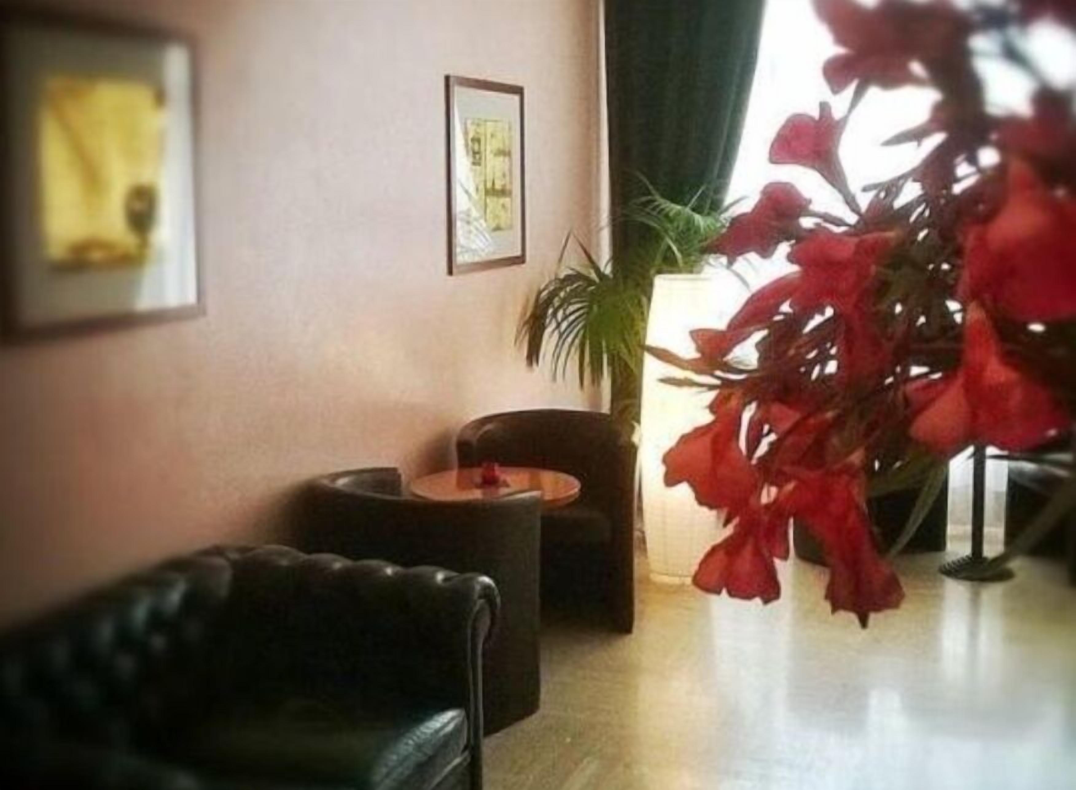 Una habitación con un sofá de cuero, una mesita redonda y una planta en maceta.