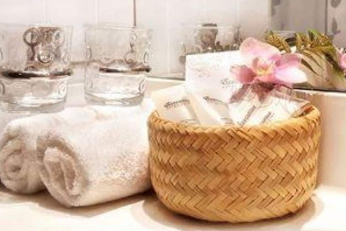 A bathroom with a towel, a woven basket, and clear glass bottles.