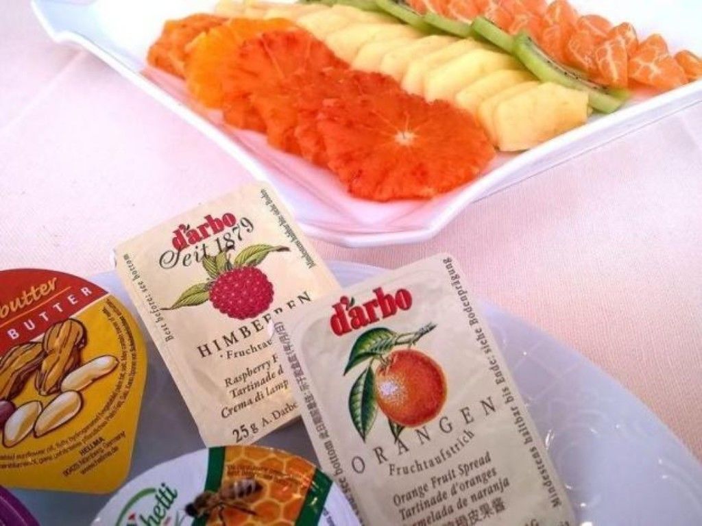A table with a fruit platter, two packets of 'd'arbó' jam, and a packet of 'd'arbó' butter.