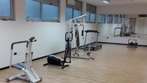 A spacious gym with exercise equipment, large windows, and a mirror wall. - Executive Hotel Udine (Udine)