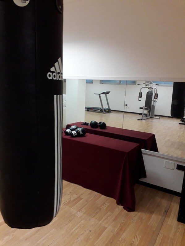 A gym with a punching bag, dumbbells, and exercise equipment. - Executive Hotel Udine (Udine)