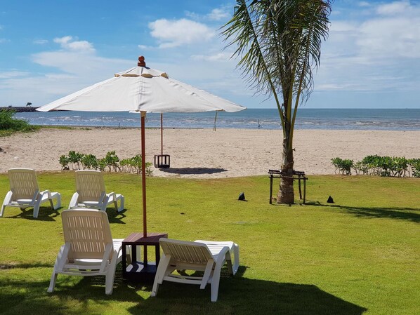 A beachside lounge with white chairs and a large umbrella, overlooking the ocean. - Triple Tree Beach Resort (Cha-am)