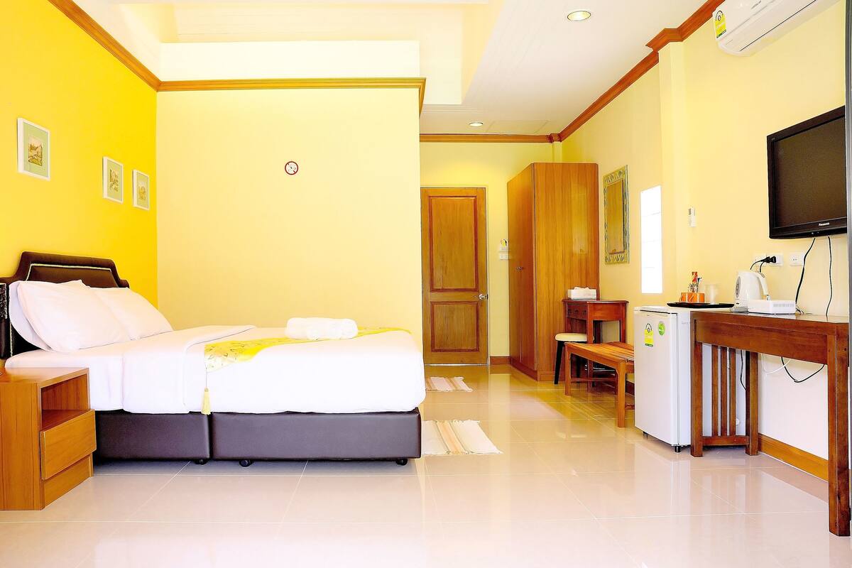 Une chambre d’hôtel comprenant un lit, des tables de chevet, un bureau avec une chaise, une télévision et un réfrigérateur.