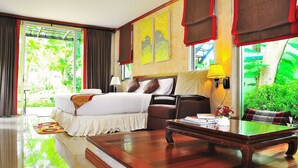 Een hotelkamer met een bed, een bureau, een stoel, een lamp en uitzicht op groen.