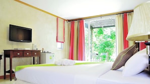 Een hotelkamer met een bed, een televisie, een bureau en een raam met gordijnen.