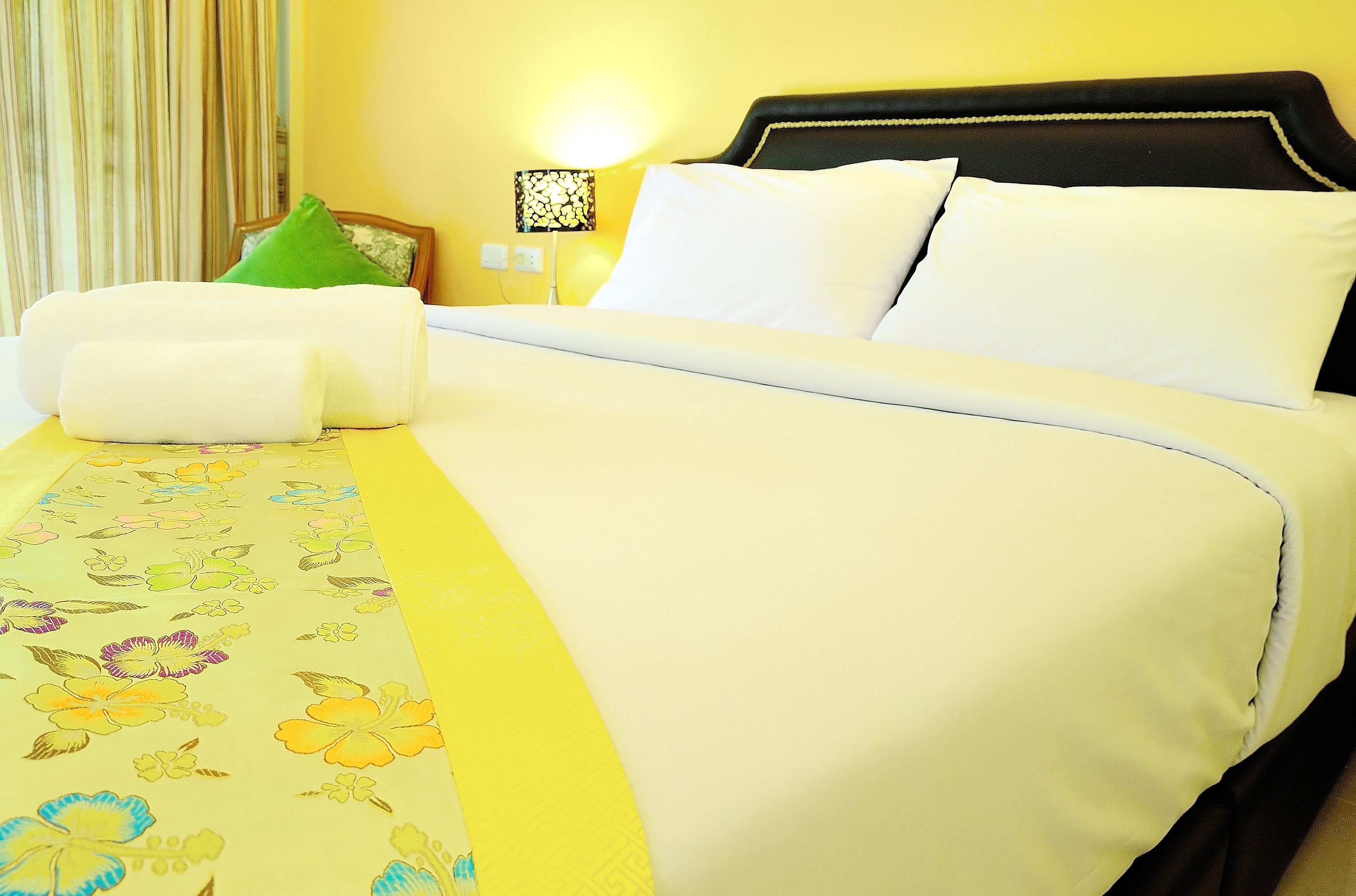 A neatly made bed with white linens and a floral-patterned bedspread.