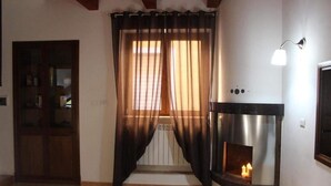 Una sala de estar con chimenea, un acceso con paneles de vidrio y una cortina.