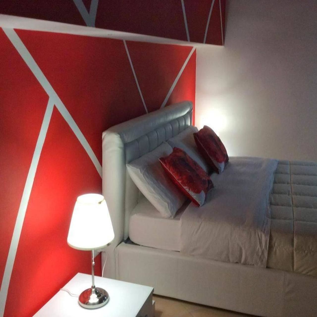 A modern bedroom with a bed, a nightstand, and a lamp.