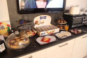 Un bufé de desayuno con diferentes alimentos y un televisor mostrando una escena.