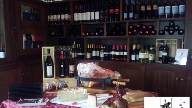 Un bar de vinos con estantes llenos de botellas, una tabla de embutidos con queso y pan, y un letrero que dice 'vinum' bistro y bar de vinos.