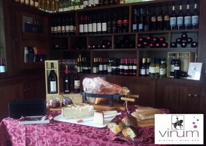 Un bar de vinos con estantes llenos de botellas, una tabla de embutidos con queso y pan, y un letrero que dice 'vinum' bistro y bar de vinos.