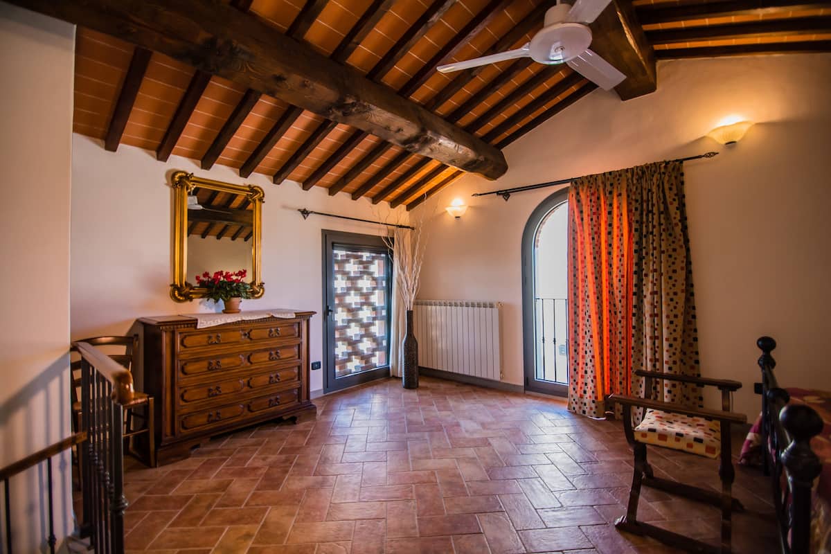 Une pièce spacieuse avec un plafond en bois, un grand miroir, une commode en bois, une chaise et un radiateur.