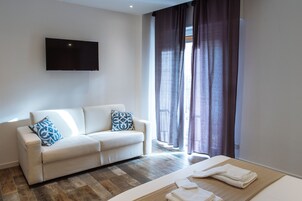 Una sala de estar moderna con un sofá, un televisor de pantalla plana y una mesa de madera con toallas.
