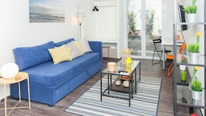 A living room with a blue sofa, a glass coffee table, and a striped rug.