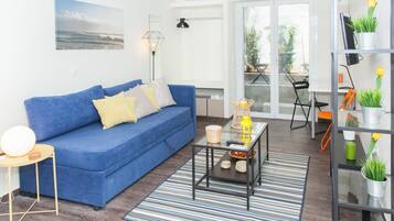 Una sala de estar con un sofá azul, una mesa de centro de vidrio y un tapete a rayas.