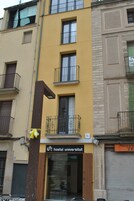 Un hostal con fachada amarilla, balcones y un letrero que indica que es un albergue universitario.