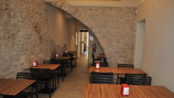 Um restaurante com paredes de pedra e mesas e cadeiras de madeira.