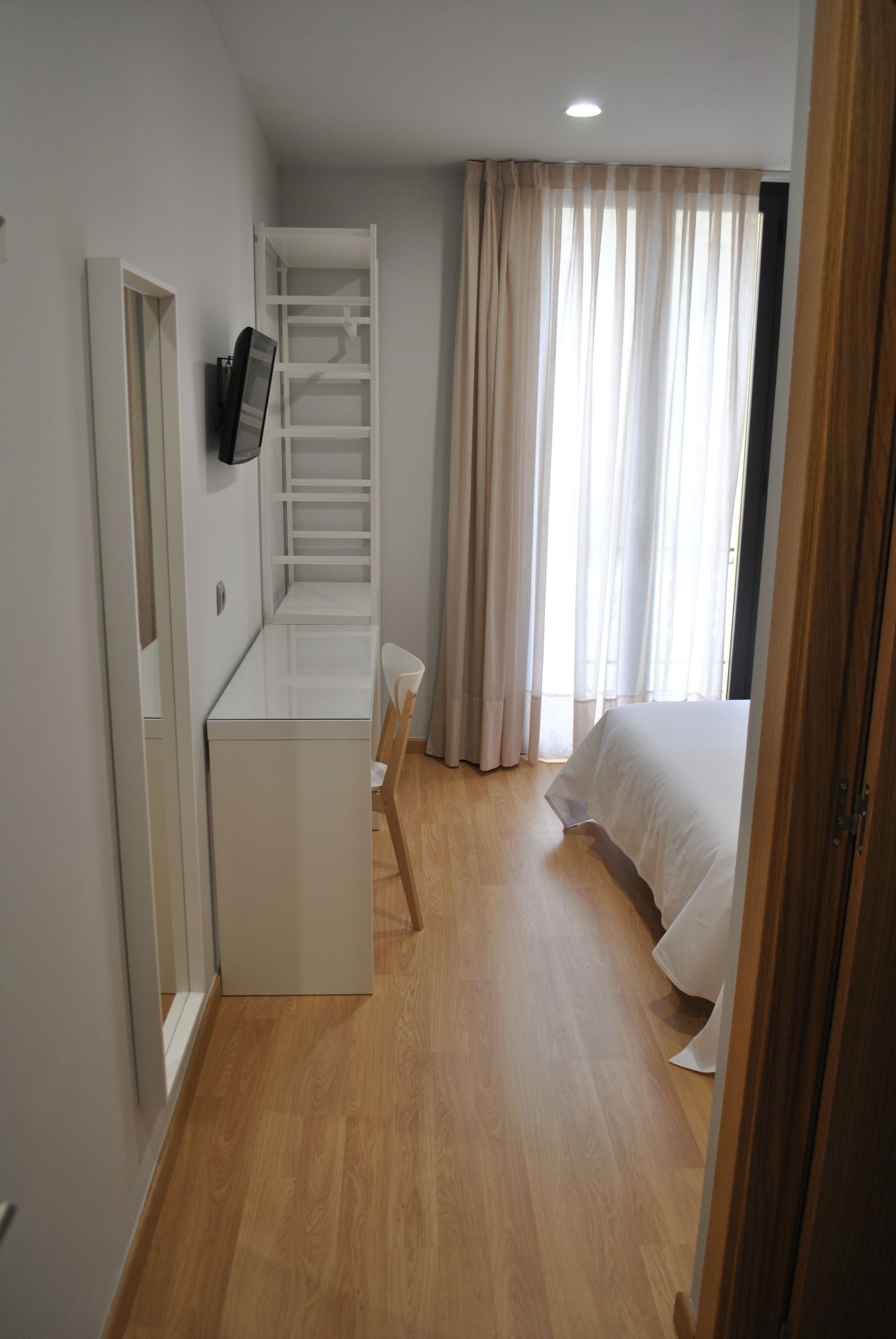 A bedroom with a bed, a desk, and a chair.