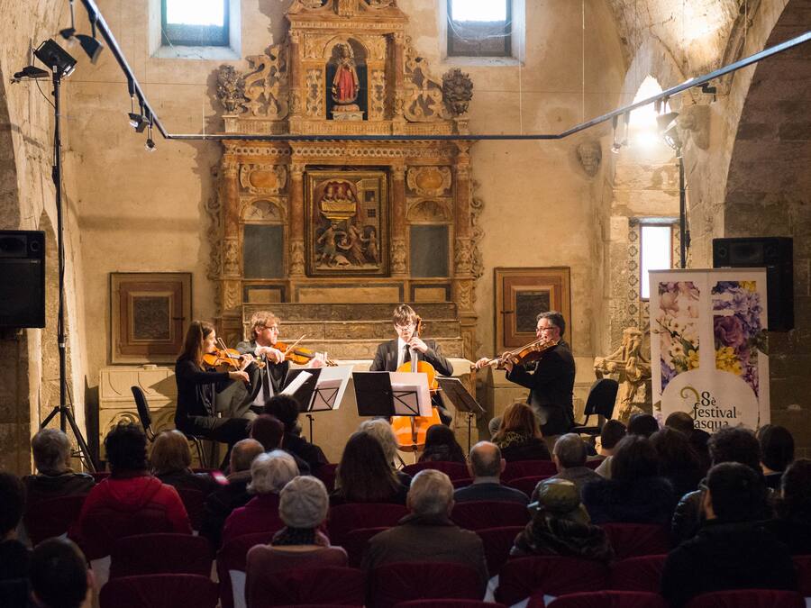 Concerto de música clássica em um edifício histórico, com o público sentado em fileiras.