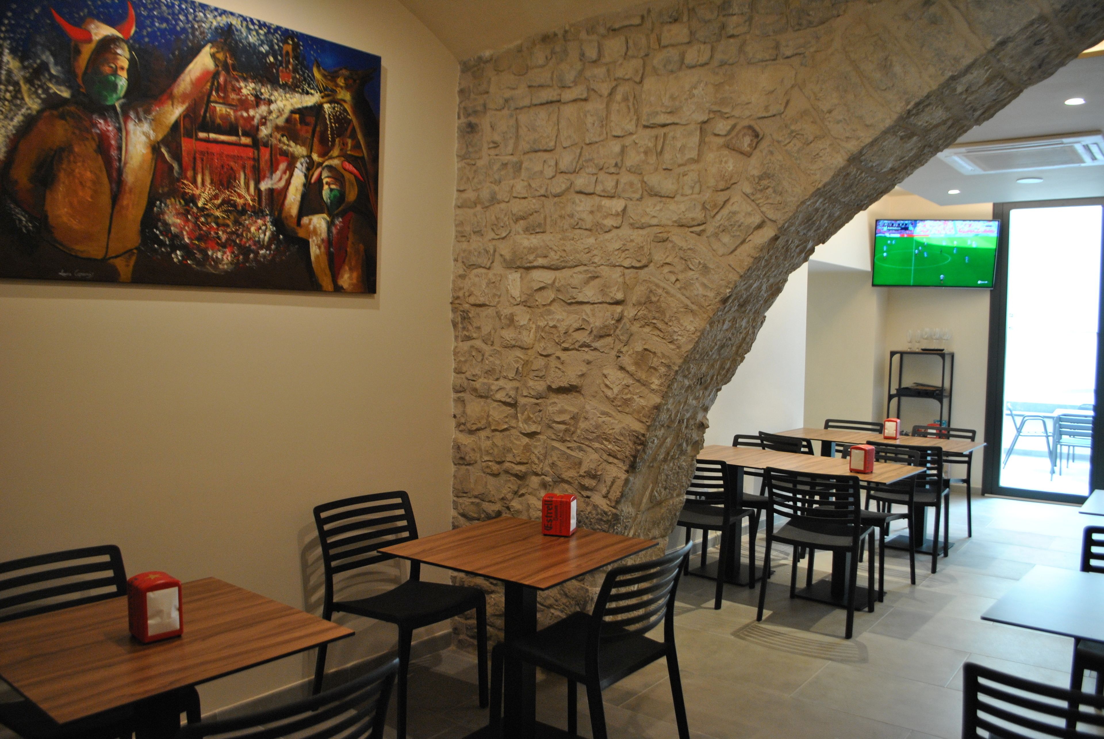 Un restaurante con paredes de piedra, mesas de madera y sillas negras.