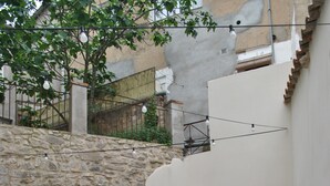 Une terrasse extérieure avec des murs en pierre, des chaises et des tables en métal.