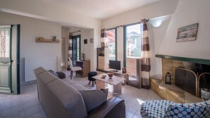 A living room with a sofa, a coffee table, a fireplace, and a television. - Ioanna's Home (Malevizi)