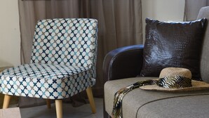 A living room with a patterned armchair, a sofa with a zebra print throw, and a hat on the sofa. - Ioanna's Home (Malevizi)