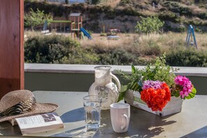 A table with a straw hat, a glass of water, a pitcher, a mug, and a flower box. - Ioanna's Home (Malevizi)