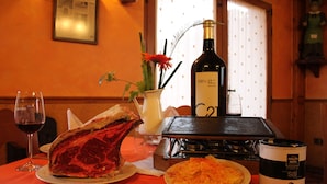 A dining table with a bottle of wine, a plate of food, and a decorative vase. - El Rincon del Labrador (Castromonte)