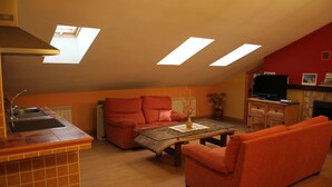 A compact living space with a kitchen area, a sofa, a coffee table, and a television. - El Rincon del Labrador (Castromonte)