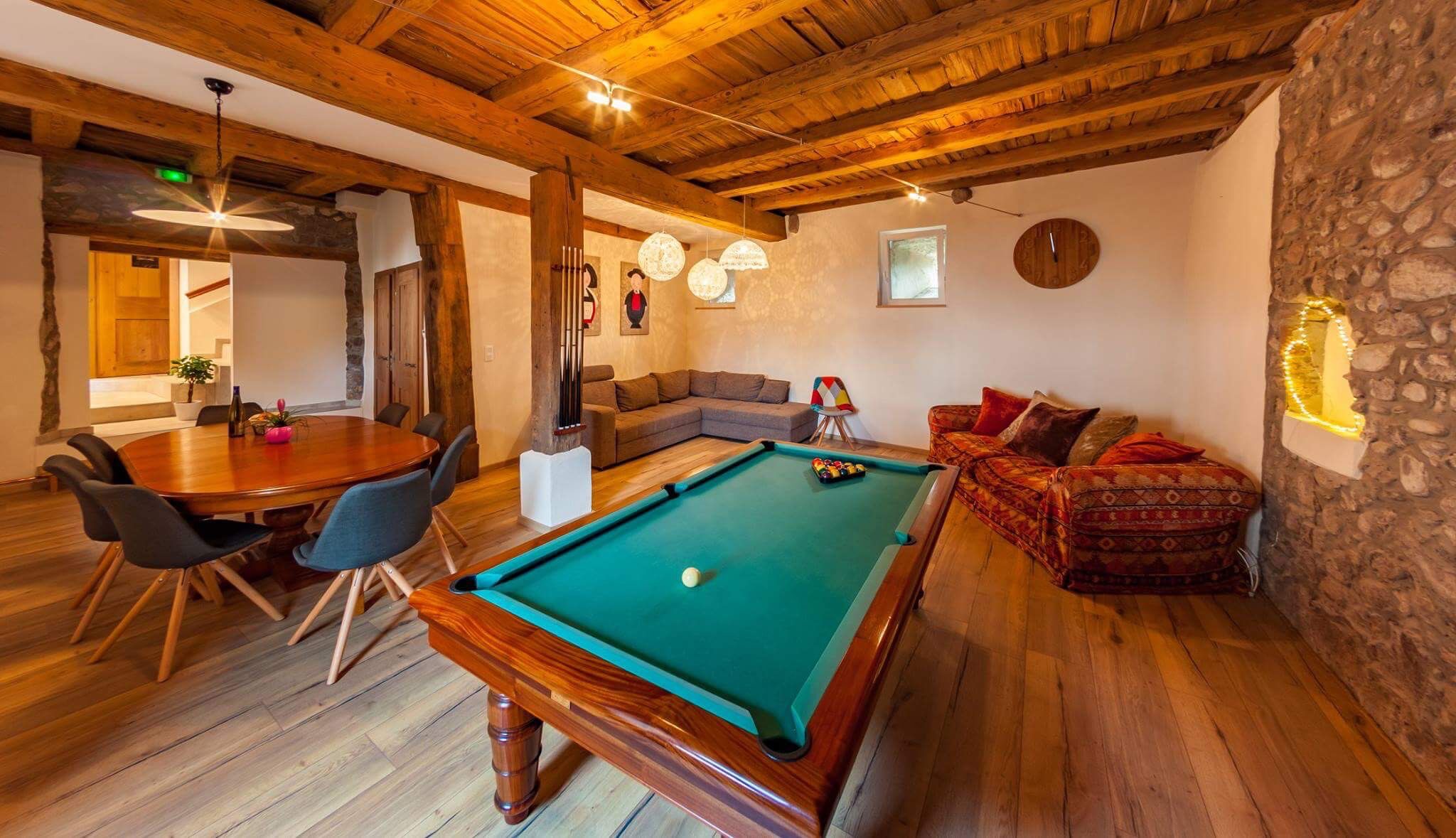 Una habitación acogedora con mesa de billar, zona de comedor y sofá.
