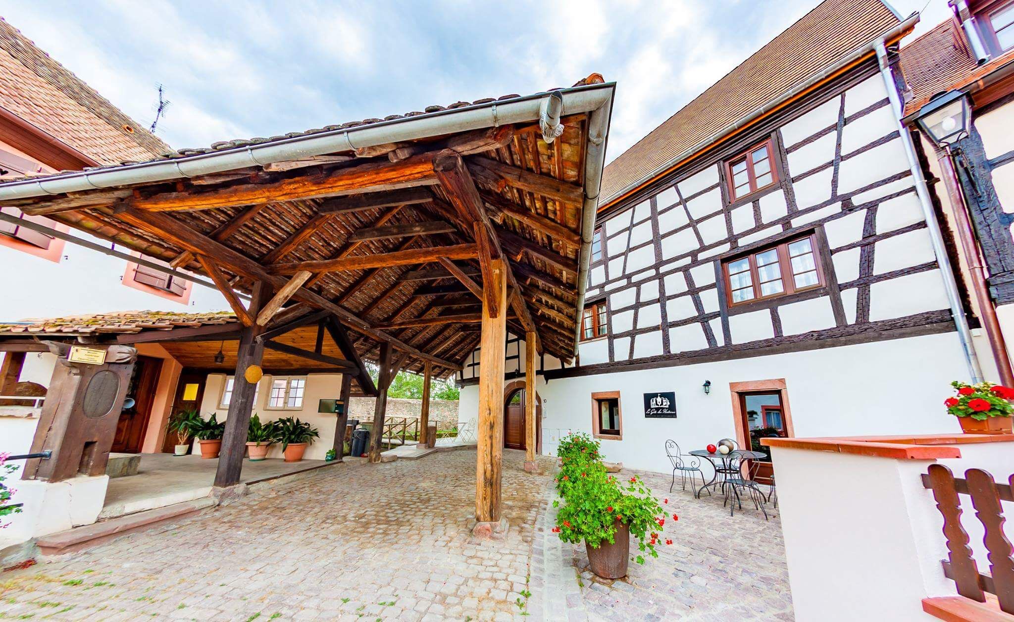 Ein traditionelles Fachwerkhäus mit überdachtem Innenhof und Kopfsteinpflaster.