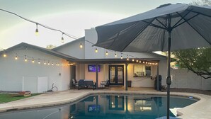 A backyard with a swimming pool, outdoor seating, and string lights. - Spacious Yard, Pool, Pet & Kid Friendly, Close to Everything! (Mesa)