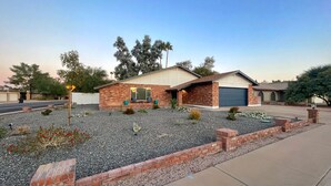 A residential house with a brick exterior, a garage, and a landscaped front yard with gravel and small plants. - Spacious Yard, Pool, Pet & Kid Friendly, Close to Everything! (Mesa)