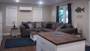Una sala moderna con un sofá modular, una mesa de centro y una pequeña zona de kitchenette.