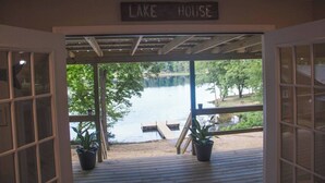 Un porche cubierto con un letrero que dice "LAKE HOUSE" y vista al lago.