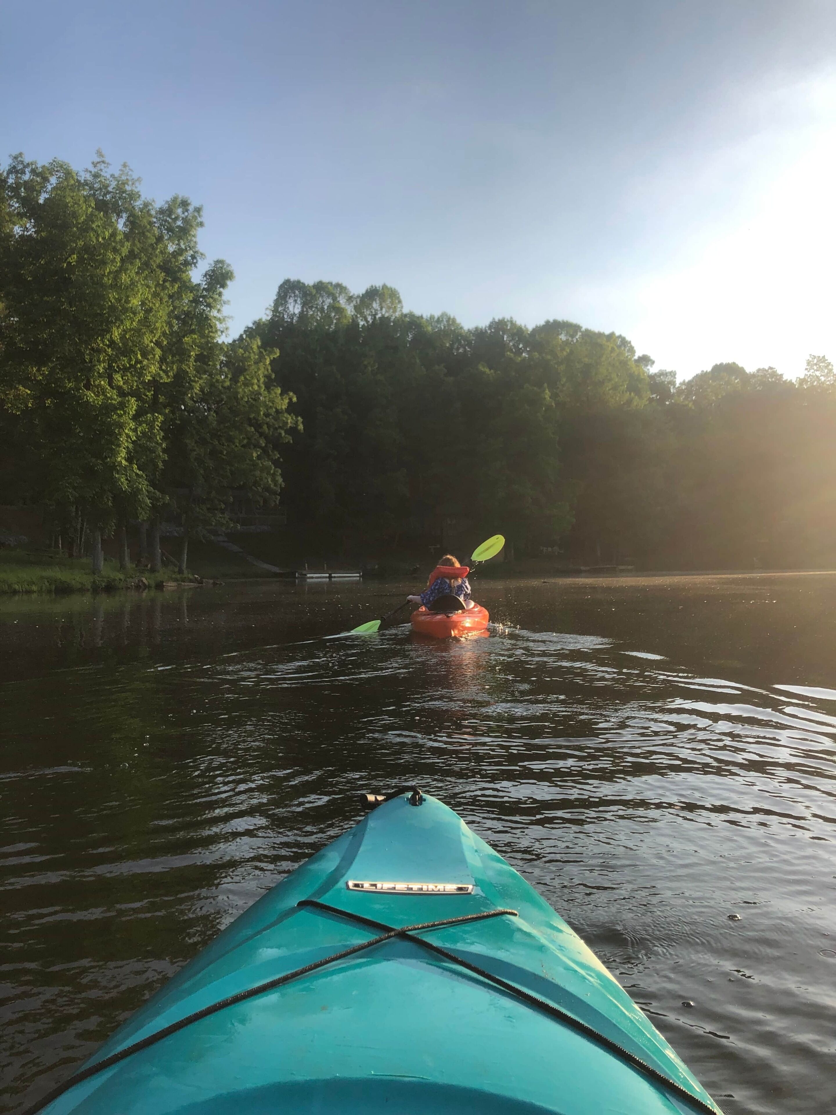 A kayak on a calm body of water with trees in the background.