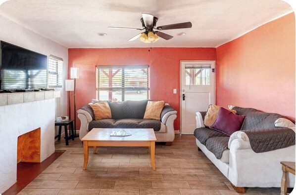 A living room with a fireplace, two couches, a coffee table, and a ceiling fan.