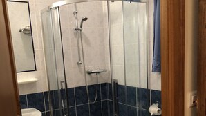 Een badkamer met een douchecabine van glas, een wit wastafelmeubel en een toilet.