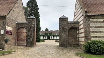 A gated entrance to a building with a brick facade and a gravel driveway.