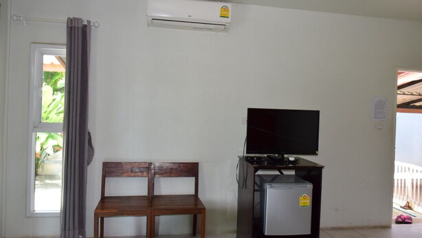 A room with a wooden bench, a television on a stand, and an air conditioner on the wall. - Sinatara Resort (Doem Bang Nang Buat)