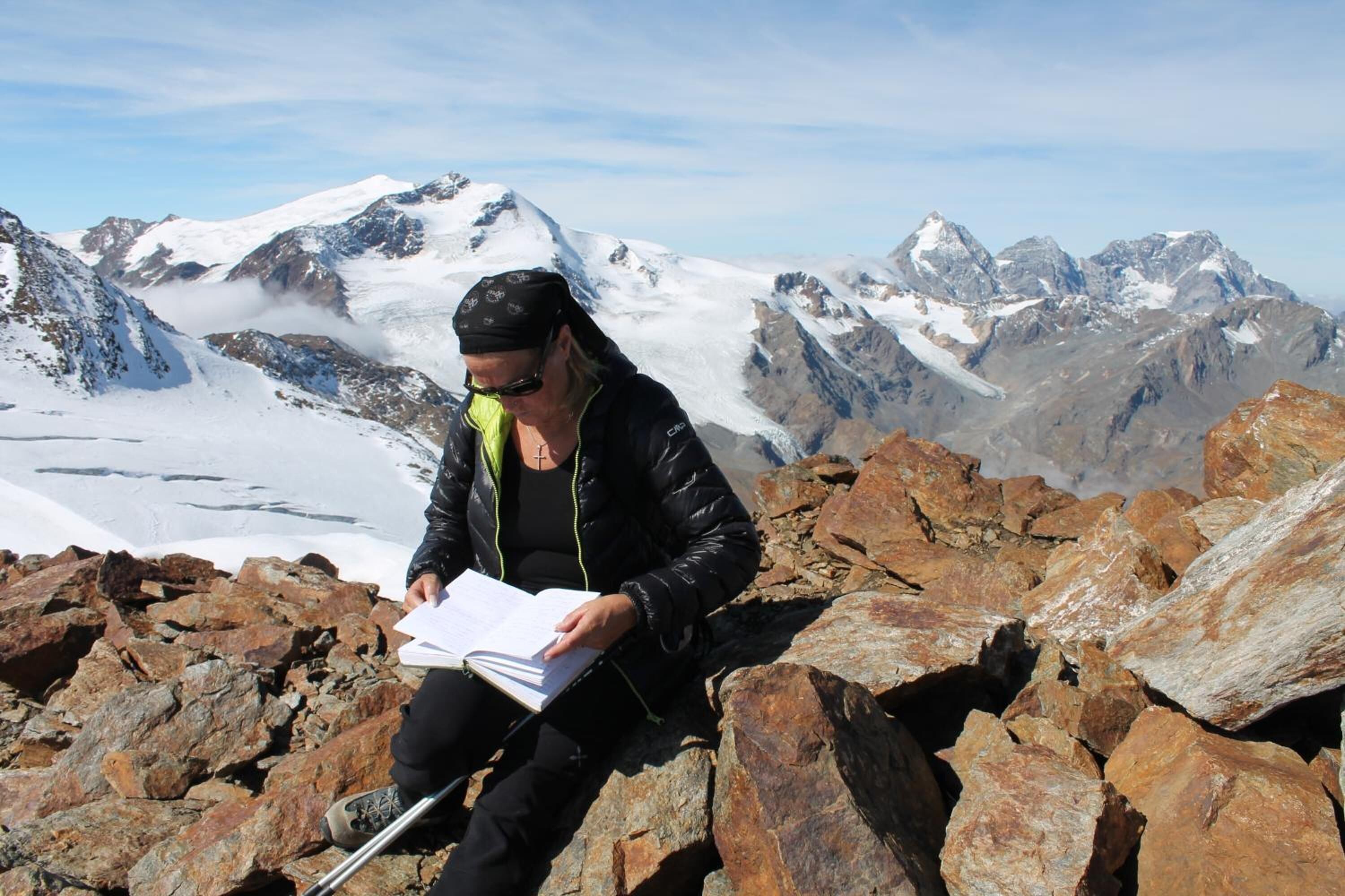 Une personne assise sur des rochers, avec un paysage montagneux en arrière-plan.