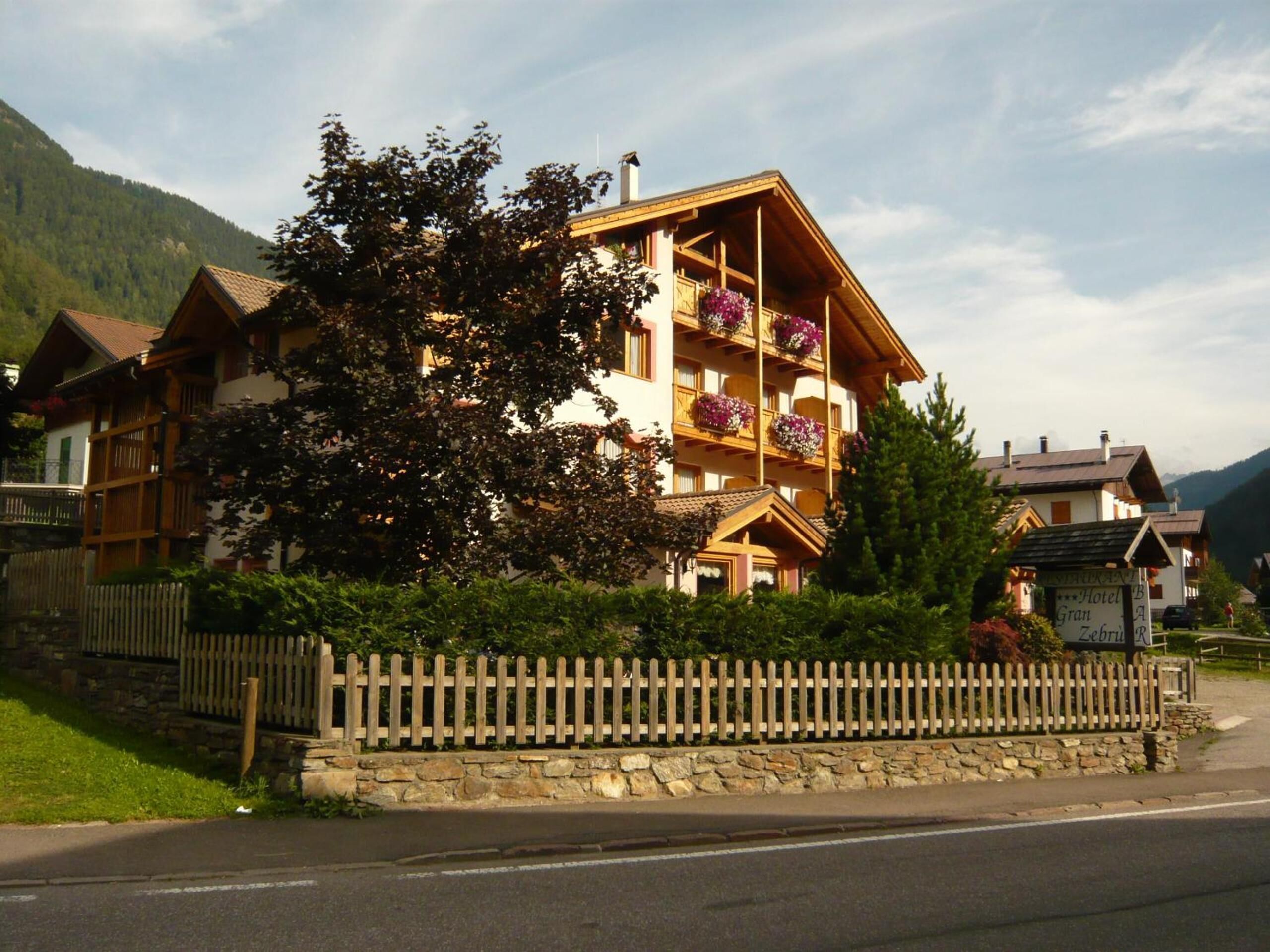 A multi-story hotel with balconies, a stone wall, and a wooden fence.