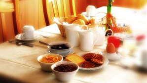 A breakfast table with various food items, a vase with flowers, and a basket. - Hotel Gran Zebrù (Pejo)