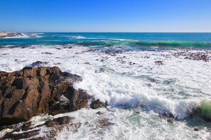 A rocky shoreline with waves crashing against the rocks. - Houghton Place Sea Point (Cape Town)