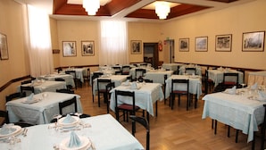 A dining area with multiple tables set for meals, featuring light blue tablecloths and wooden chairs. - Hotel Da Remo (Roccaraso)