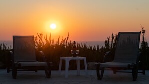 Two chairs and a table with wine glasses on a terrace overlooking the ocean at sunset. - Adonis Villa (Pegeia)